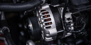 Close-up of a car alternator with visible copper wiring and belts.